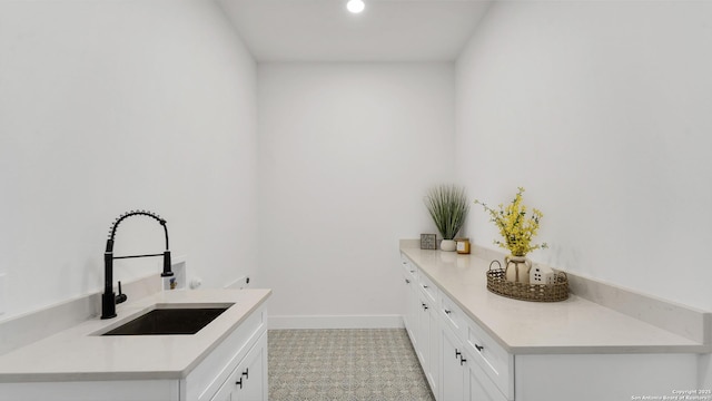 washroom featuring hookup for a washing machine, a sink, cabinet space, and baseboards