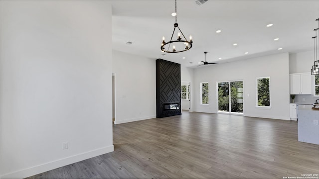 unfurnished living room featuring a fireplace, baseboards, wood finished floors, and recessed lighting