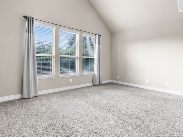 carpeted spare room featuring vaulted ceiling and baseboards