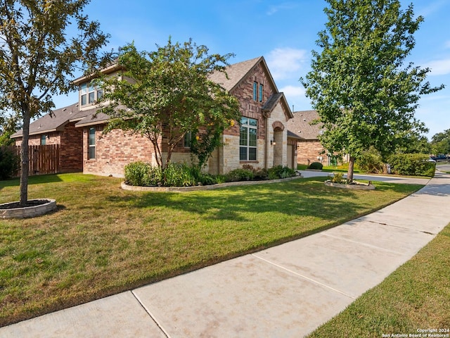 view of front of home with a front yard, stone siding, brick siding, and fence