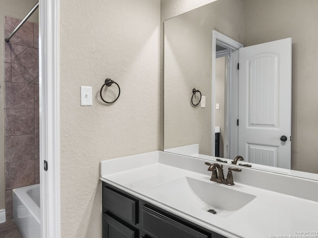 full bathroom featuring bathtub / shower combination, a textured wall, and vanity