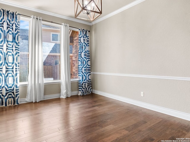 empty room with baseboards, a chandelier, wood finished floors, and ornamental molding