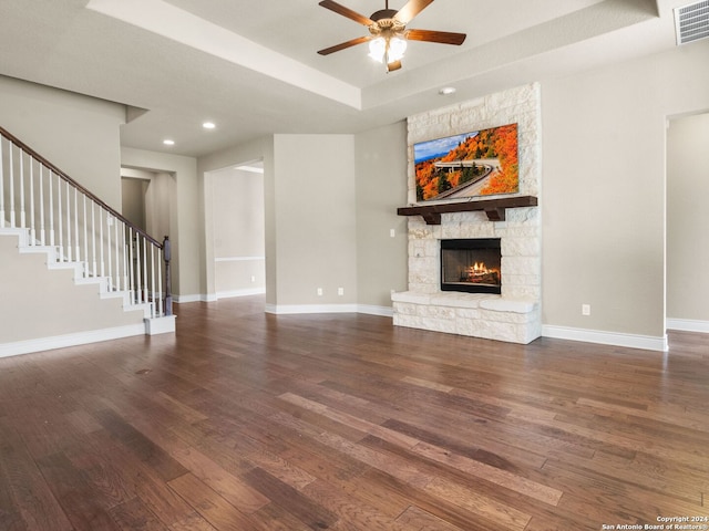 unfurnished living room featuring a raised ceiling, visible vents, wood finished floors, baseboards, and stairs