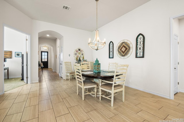 dining space featuring baseboards, visible vents, arched walkways, wood finish floors, and a notable chandelier