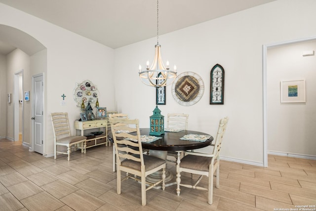 dining room featuring a notable chandelier, wood tiled floor, arched walkways, and baseboards