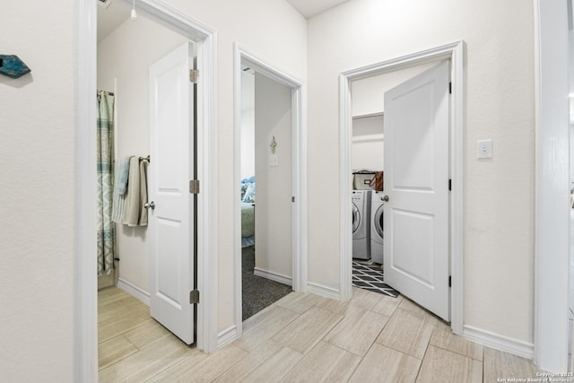 corridor featuring wood finish floors, independent washer and dryer, and baseboards