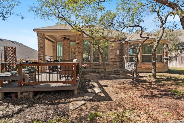 rear view of property with ceiling fan, fence, a deck, and brick siding