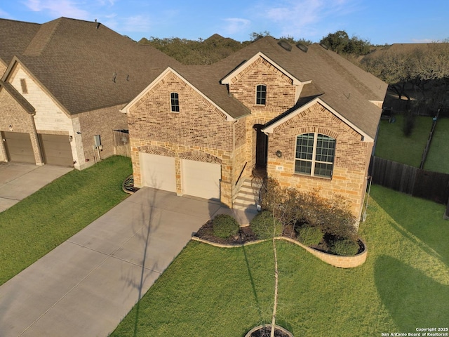 view of front of property featuring driveway, brick siding, a front yard, and fence