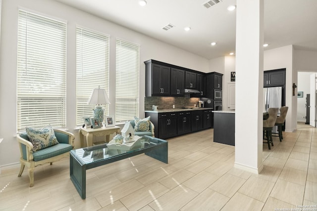 kitchen with under cabinet range hood, dark cabinets, stainless steel appliances, visible vents, and light countertops