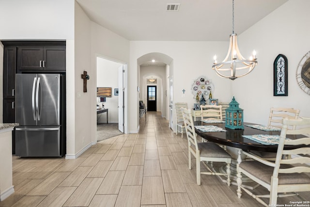 dining space featuring arched walkways, visible vents, baseboards, wood tiled floor, and an inviting chandelier