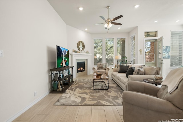 living room featuring a warm lit fireplace, baseboards, wood finished floors, and recessed lighting