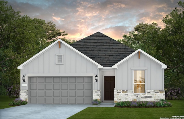 view of front of home featuring roof with shingles, board and batten siding, a front yard, a garage, and driveway