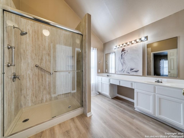 full bathroom with a stall shower, vaulted ceiling, a healthy amount of sunlight, and a sink