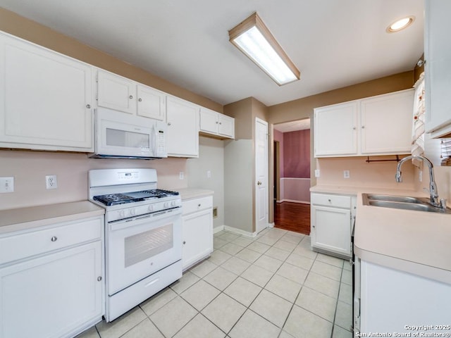 kitchen featuring white appliances, white cabinets, and a sink