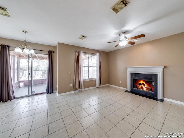 unfurnished living room with light tile patterned floors, ceiling fan with notable chandelier, a glass covered fireplace, and visible vents