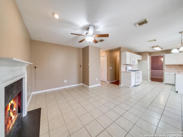 unfurnished living room with visible vents, light tile patterned flooring, a lit fireplace, baseboards, and ceiling fan with notable chandelier