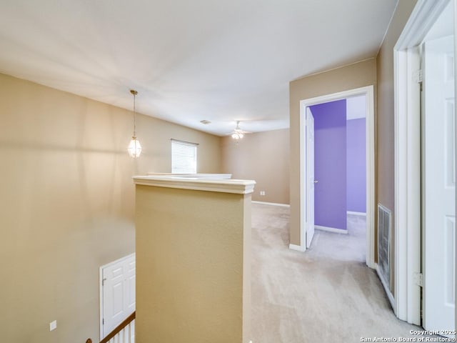 hall featuring light carpet, visible vents, baseboards, and an upstairs landing