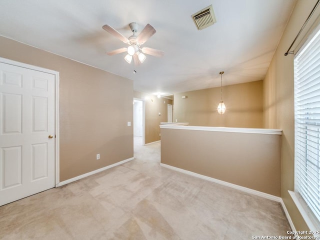 unfurnished room featuring light carpet, baseboards, visible vents, and a ceiling fan