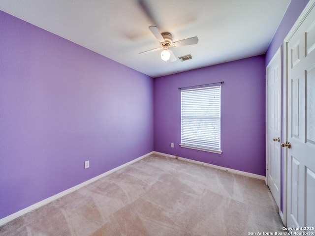 empty room featuring carpet, visible vents, ceiling fan, and baseboards