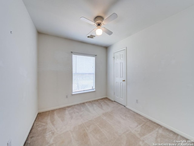 empty room with light colored carpet, visible vents, ceiling fan, and baseboards