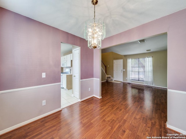 unfurnished room with baseboards, stairs, visible vents, and wood finished floors