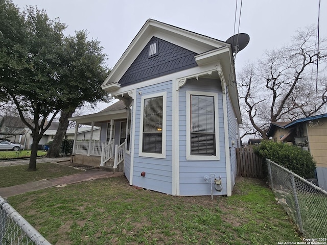 view of property exterior with fence, a porch, and a yard