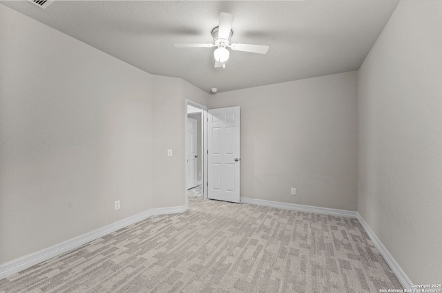 empty room featuring baseboards, a ceiling fan, and light colored carpet