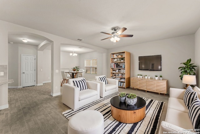 living area with arched walkways, visible vents, baseboards, and ceiling fan with notable chandelier