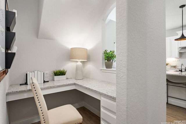 office featuring arched walkways, a textured wall, and dark wood finished floors