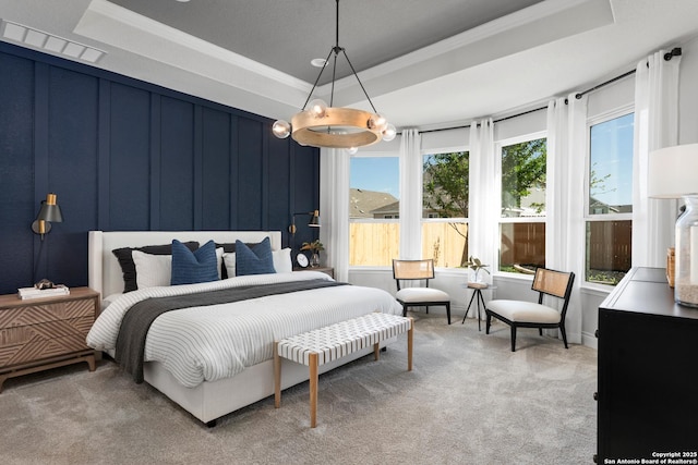 carpeted bedroom featuring a raised ceiling, visible vents, crown molding, and a decorative wall