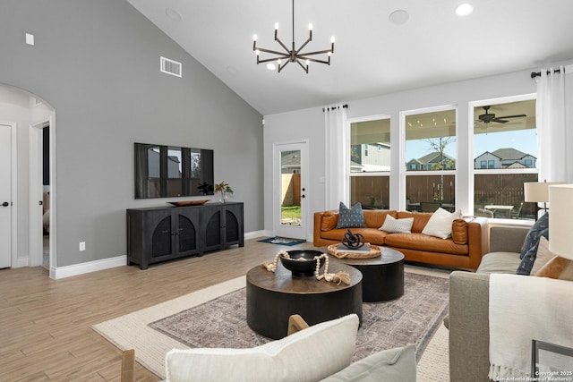 living room featuring visible vents, arched walkways, a chandelier, wood finished floors, and high vaulted ceiling