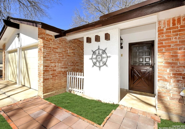 view of exterior entry with a garage and brick siding