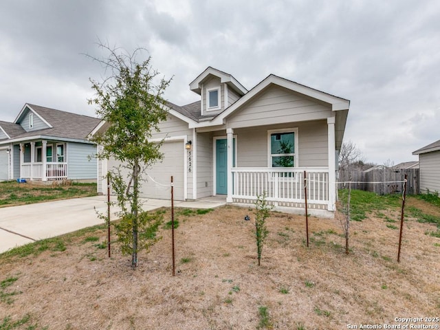 view of front of home featuring a garage, covered porch, driveway, and fence