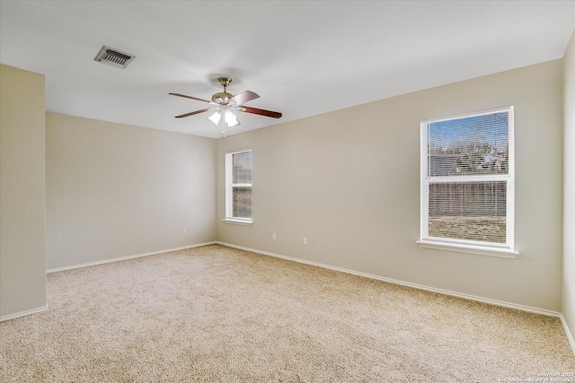 spare room with ceiling fan, carpet, visible vents, and a healthy amount of sunlight