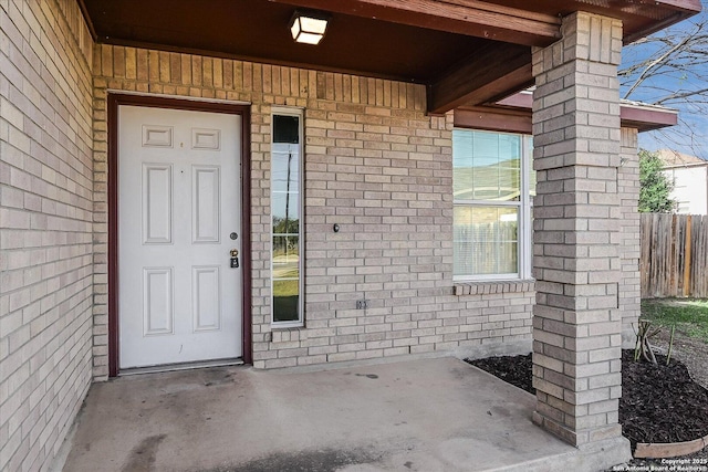 property entrance featuring fence and brick siding