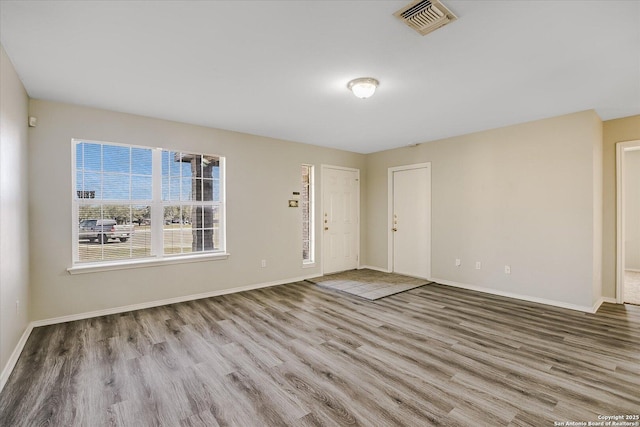 spare room featuring visible vents, baseboards, and wood finished floors