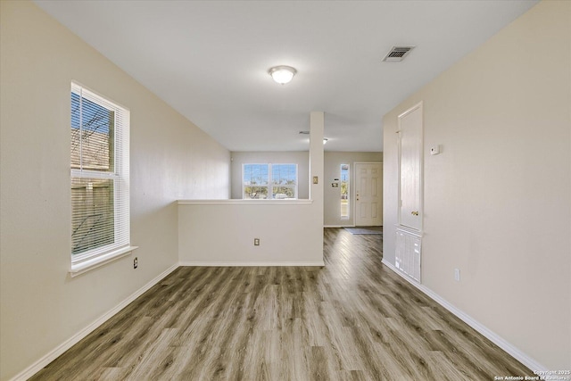 spare room featuring wood finished floors, visible vents, and baseboards