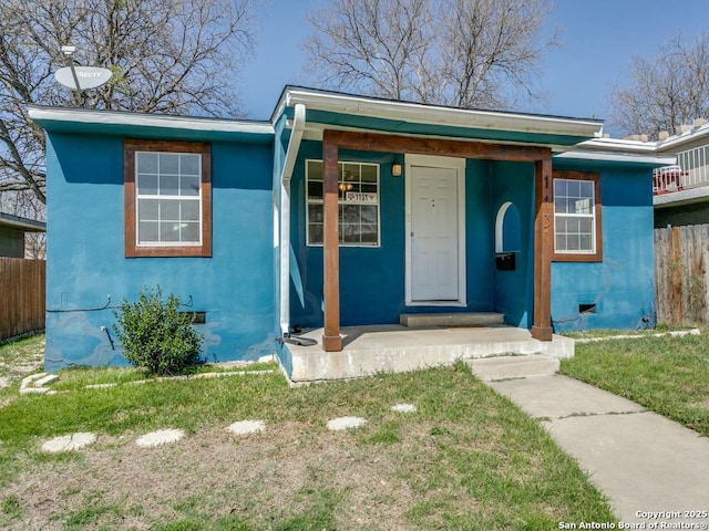 bungalow-style house with crawl space, a front yard, fence, and stucco siding