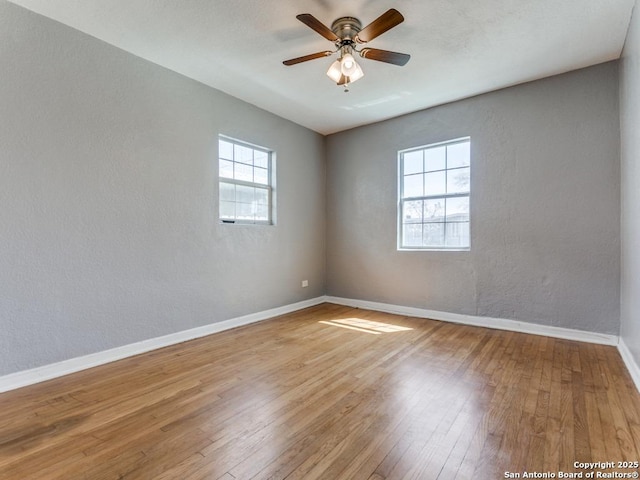 empty room with a ceiling fan, baseboards, a textured wall, and hardwood / wood-style floors