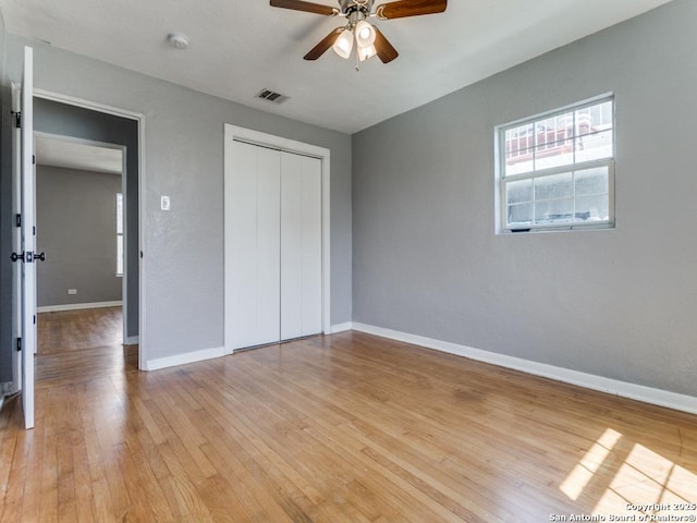 unfurnished bedroom featuring light wood-type flooring, visible vents, baseboards, and a closet