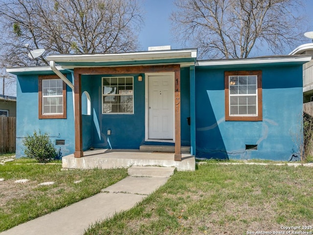 bungalow-style home featuring a front lawn, crawl space, fence, and stucco siding