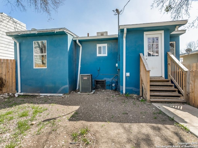 back of property featuring stucco siding, cooling unit, and fence