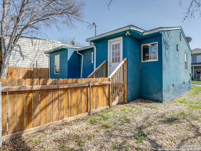 back of property featuring crawl space, fence, and stucco siding