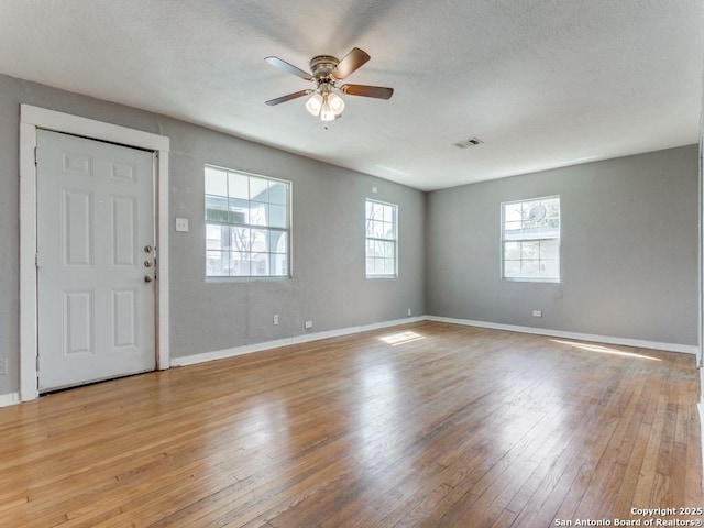 entrance foyer with a textured ceiling, visible vents, baseboards, a ceiling fan, and light wood-type flooring