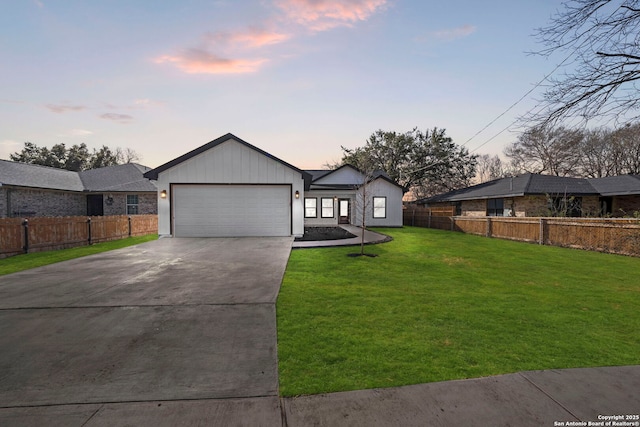 view of front of home featuring driveway, a front lawn, an attached garage, and fence