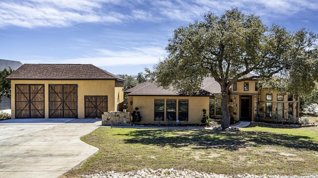 view of front of home with a garage, roof with shingles, an outbuilding, a front lawn, and stucco siding