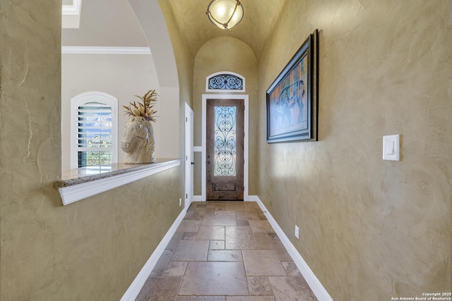 doorway with baseboards, vaulted ceiling, and stone tile floors