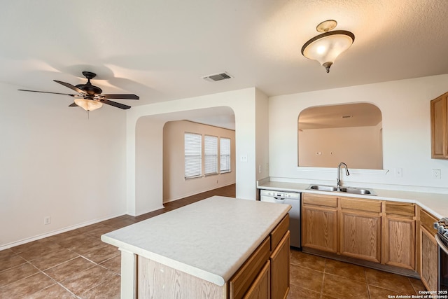 kitchen featuring dishwashing machine, light countertops, a sink, and visible vents