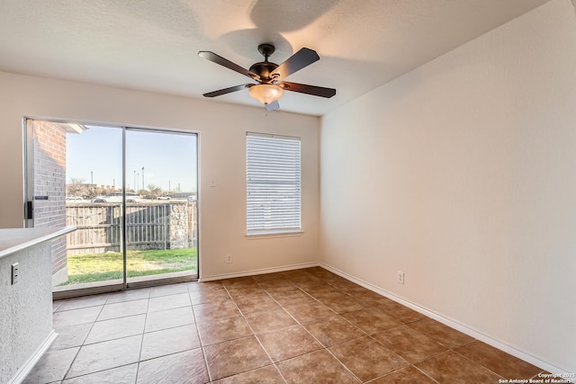 empty room featuring ceiling fan, a textured ceiling, baseboards, and light tile patterned floors