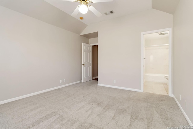 unfurnished bedroom featuring baseboards, visible vents, lofted ceiling, ensuite bath, and carpet flooring